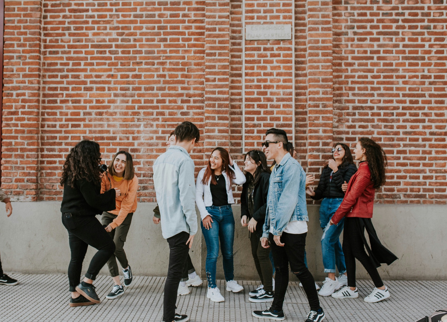A group of friends laughing together beside a brick wall