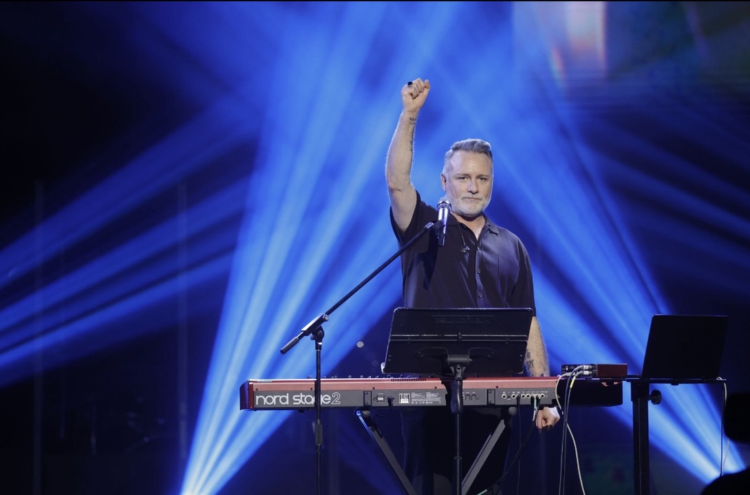 Mark Stevens performing at a keyboard under blue stage lighting