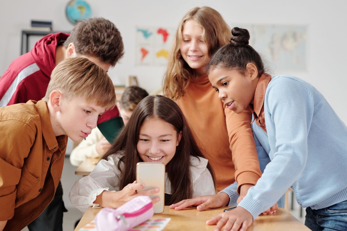 Students gathered around a smartphone in a classroom