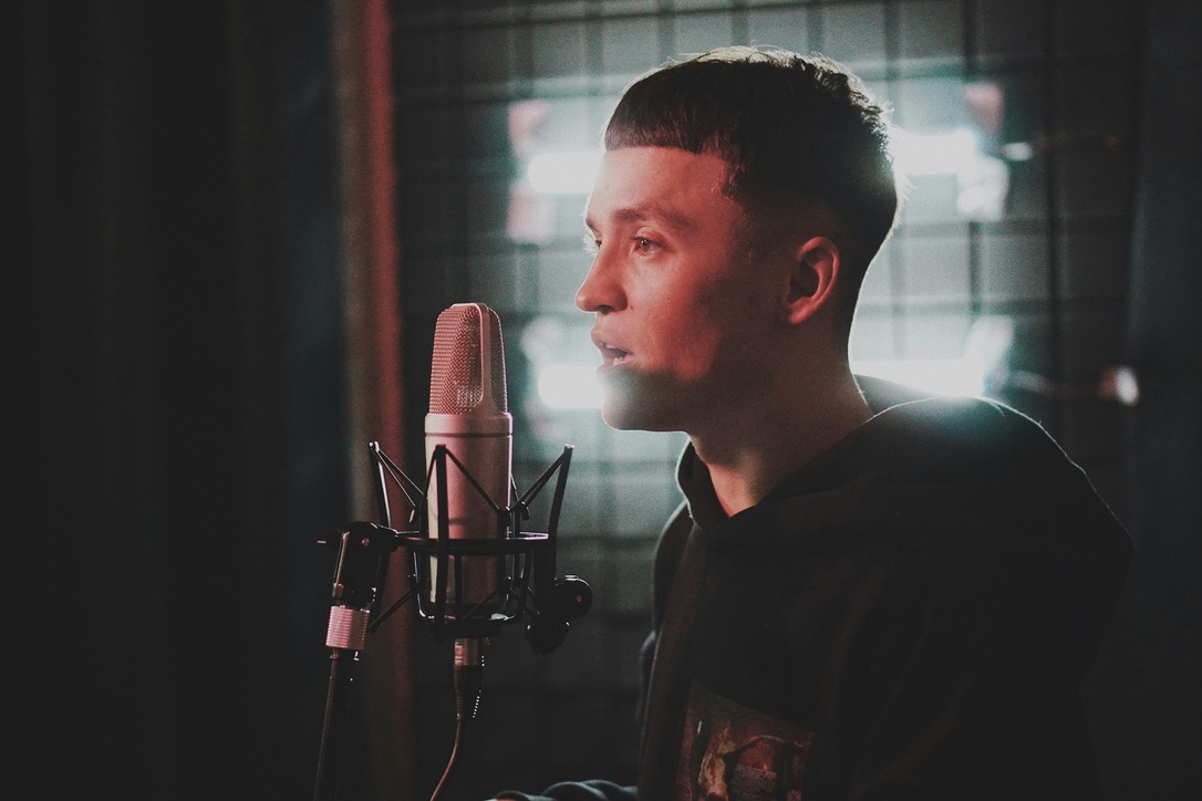 A young person recording vocals in a music studio